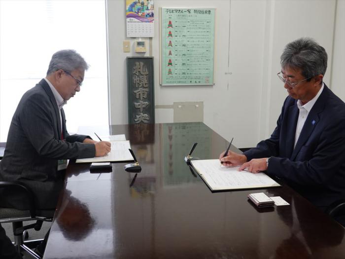 覚書にサインする（左）中川区長と（右）谷村代表取締役