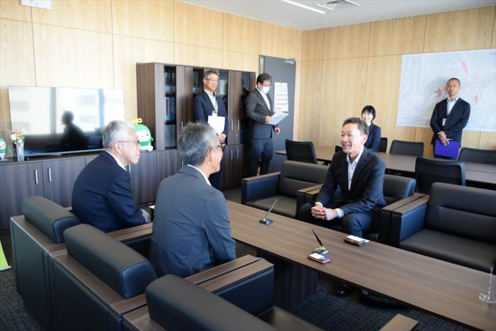 歓談する八並代表取締役社長（右）と庄中（しょうなか）市民部長（手前左）、久道区長（手前右）