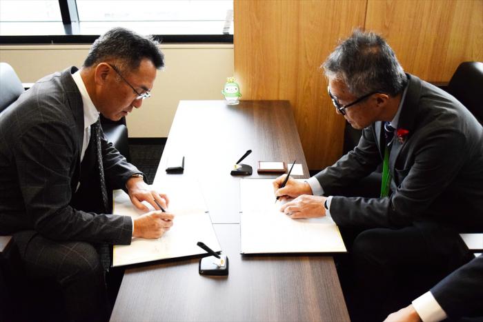 覚書にサインをする宮西支社長（左）と久道区長（右）