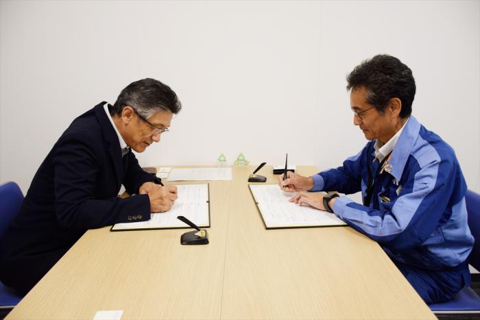 覚書にサインする（左）本間課長と（右）庄田グループリーダー