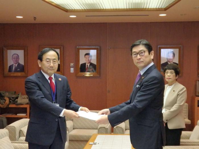 藤江代表監査委員（左）から報告書の手交を受ける飯島議長（右から2人目）としのだ副議長（右から1人目）