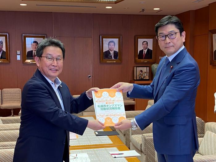田村代表オンブズマンから報告書の手交を受ける飯島議長（右）