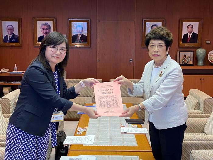 品川代表から報告書の手交を受けるしのだ副議長（右）