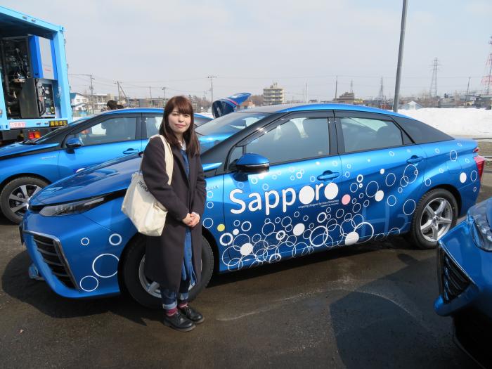 デザインをした山本さんと燃料電池自動車の写真