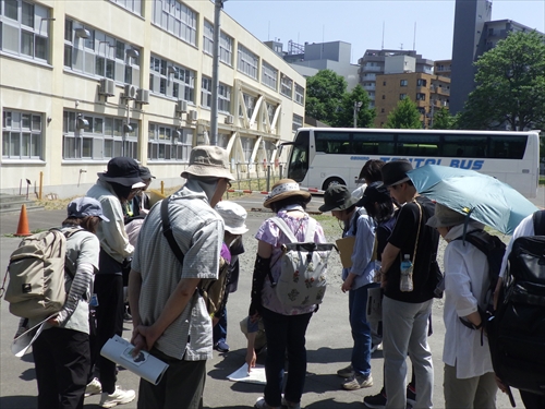 豊水小学校跡地で地形を眺めるツアー参加者の様子