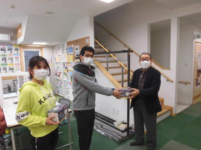 小田島連町会長からマスクが贈呈されるネオロス代表石川さん（中央）と副代表の長山さん（左）