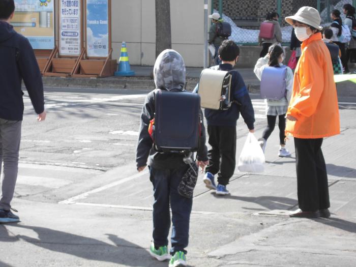 交通安全指導員が横断歩道で児童たちを安全に誘導している様子