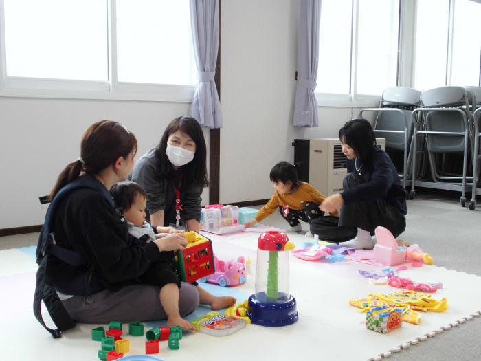 おもちゃで遊びながら話をしている3組の親子