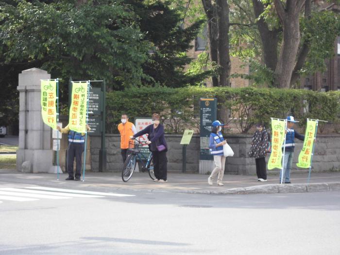 北海道大学正門前で幟を持って街頭啓発を行う交通指導員のみなさん様子