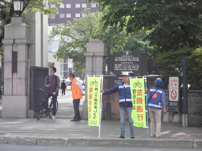 北海道大学正門前で幟を持って街頭啓発を行う交通指導員のみなさん様子