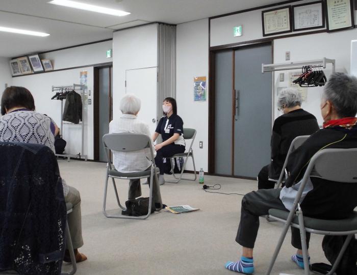 受講者を前に椅子に座った状態で参加者たちに説明している講師の様子
