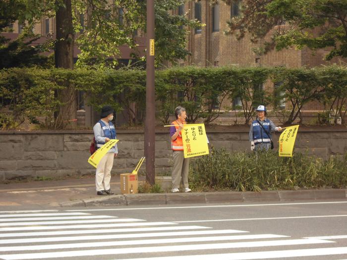北海道大学正門前で交通安全の小旗を持って街頭啓発を行っている参加者の様子