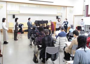 高齢者の周囲の関係機関の担当者が挨拶をしている様子