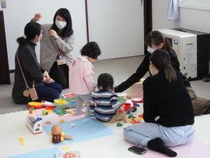 二組の親子が一緒におもちゃで遊んでいる様子