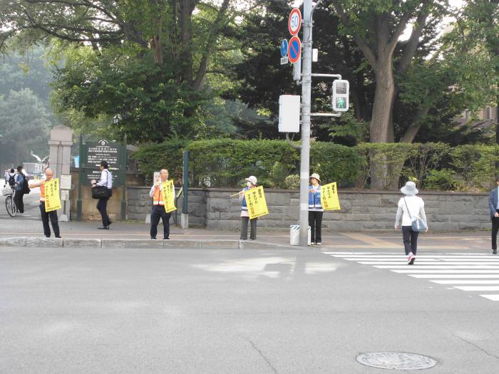 北海道大学正門前で交通安全の小旗を持って街頭啓発を行っている参加者の様子