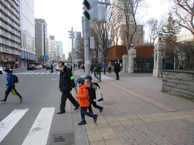 安全のため新1年生2人と一緒に横断歩道を渡る交通部の男性の様子