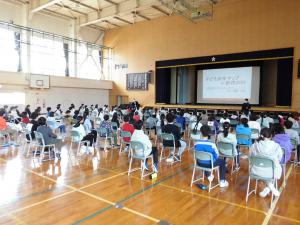 小学校体育館で「まち歩き」の事前説明を鉄西まちづくりセンター所長から受ける6年生の様子