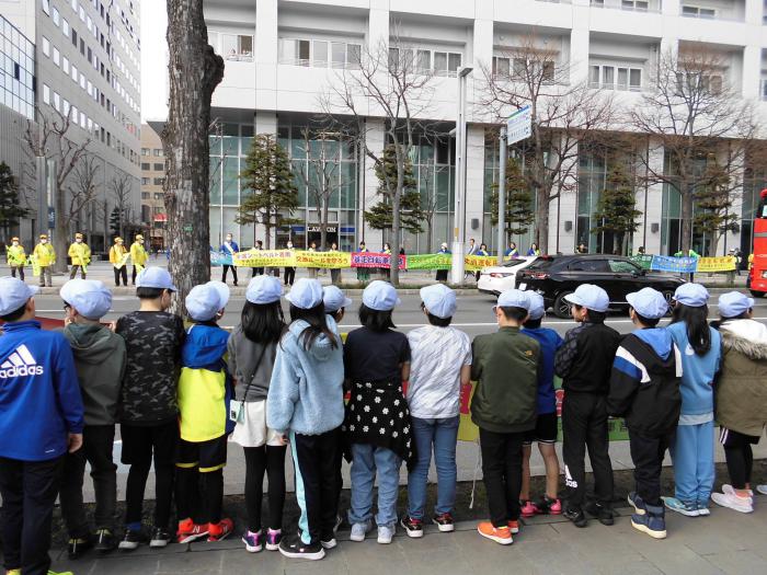 横断幕を掲げる北九条小学校の皆さんと地元企業の