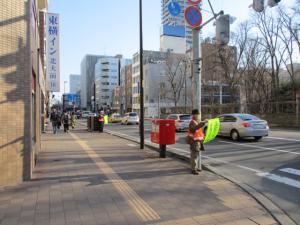 地域の方が交通安全の旗を持ち、樽川通沿いのドライバーさんに交通安全を呼び掛けている様子