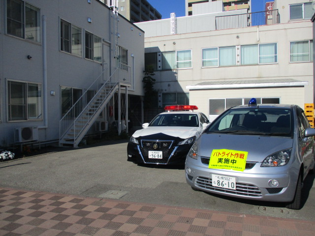 会館の駐車場にパトカーやパトライトの車が止まっている様子