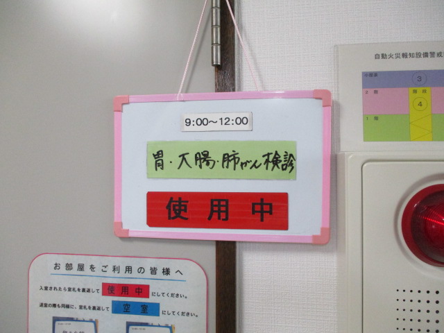 がん検診が行われる部屋の前に「胃・大腸・肺がん検診」の看板が掛けられている写真
