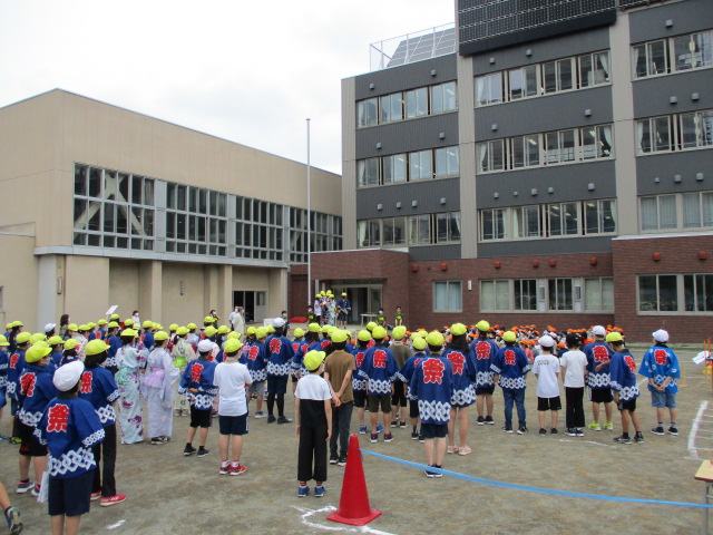 北九条小学校のグラウンドで、浴衣や法被姿の子どもたちが集合し、これから始まるお祭りを心待ちにしている様子