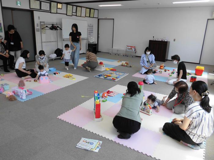 部屋の中に用意されたたくさんのおもちゃで遊んでいる数組の親子の様子
