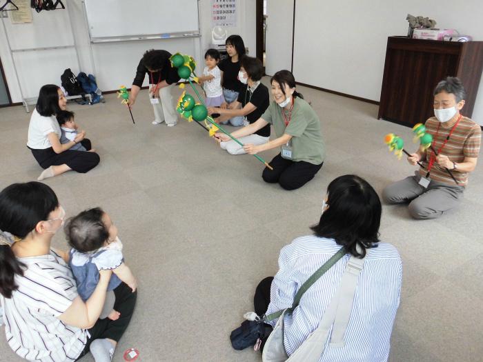 スタッフが操るペープサート（棒の先に人形がついているもの）を楽しむ親子