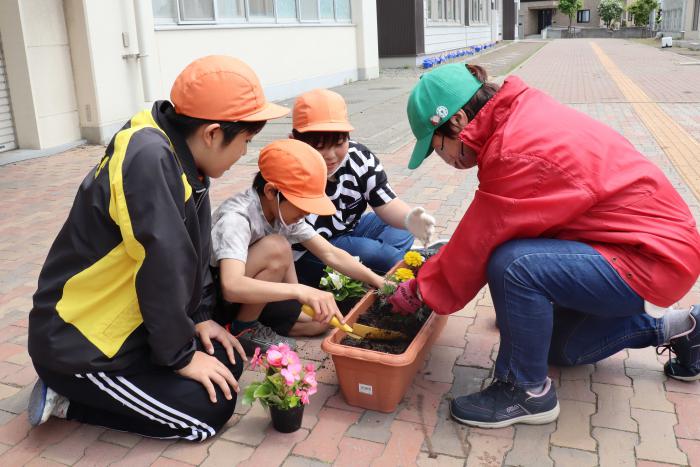 花を植える子どもたちとボランティアの方