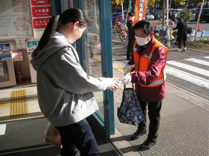 店舗入口にて啓発品を手渡しする防火委員さん