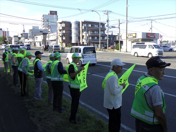 羊ヶ丘通り沿いで小旗を手に交通安全を訴えます