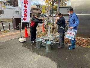 手動ポンプを使用して給水作業を行う参加者