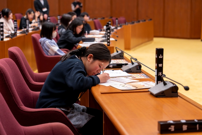 本会議場でメモを取る子ども議員