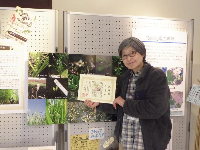 山崎学芸員が感謝状を持っている写真