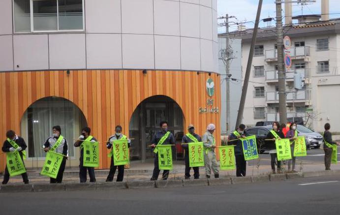 シートベルト着用と書かれた旗を手に交通安全を呼びかける様子