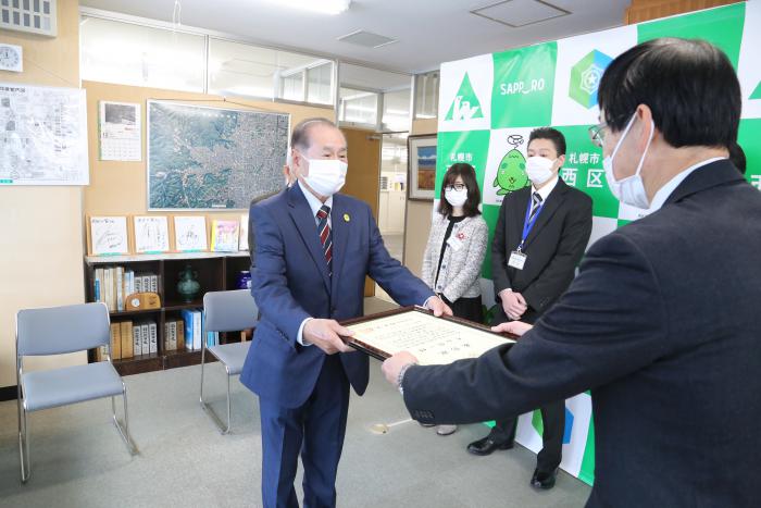 表彰状を受け取る外山さんの写真