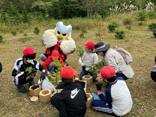 子どもが木の苗を持っている写真
