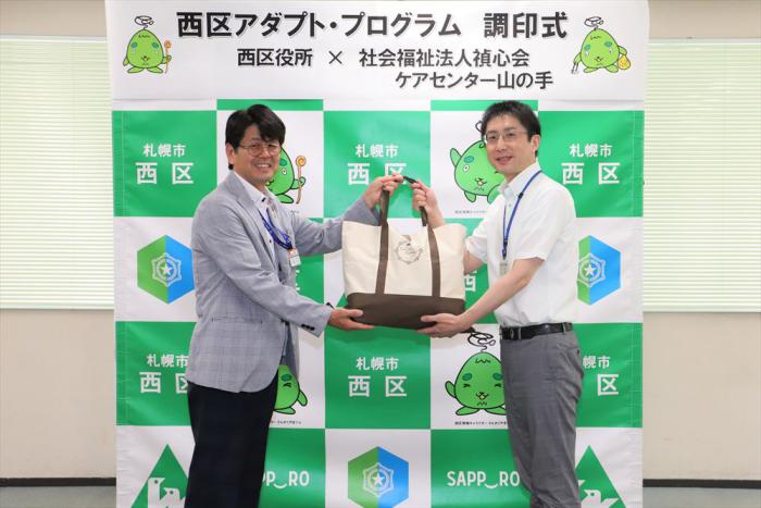 清掃用品贈呈の様子（左：村上西区長、右：ケアセンター山の手佐藤さん）