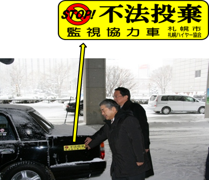 不法投棄防止用ステッカーをタクシーに貼り付けている様子