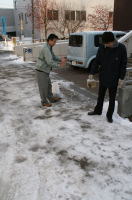 画像：区役所周辺の道路に滑り止め材を散布する職員
