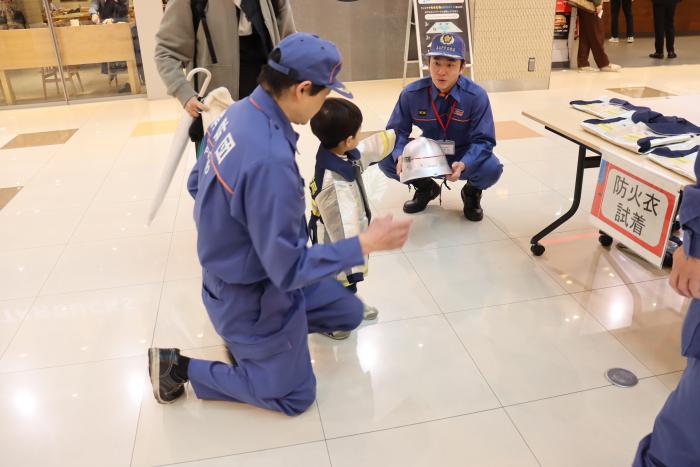 防火衣を試着する子どもの写真