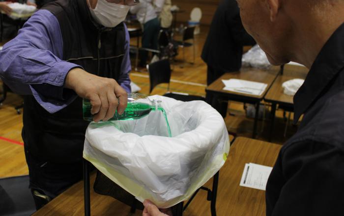 避難所の災害時用トイレに色付き水を流して実験している様子
