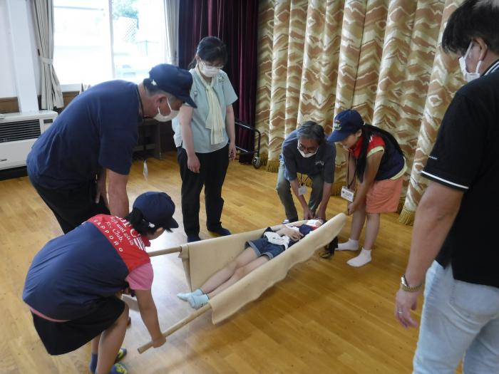 毛布で担架を作る小学生クラブ員