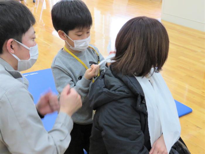 子どもが三角巾を使った応急手当の練習をしている様子