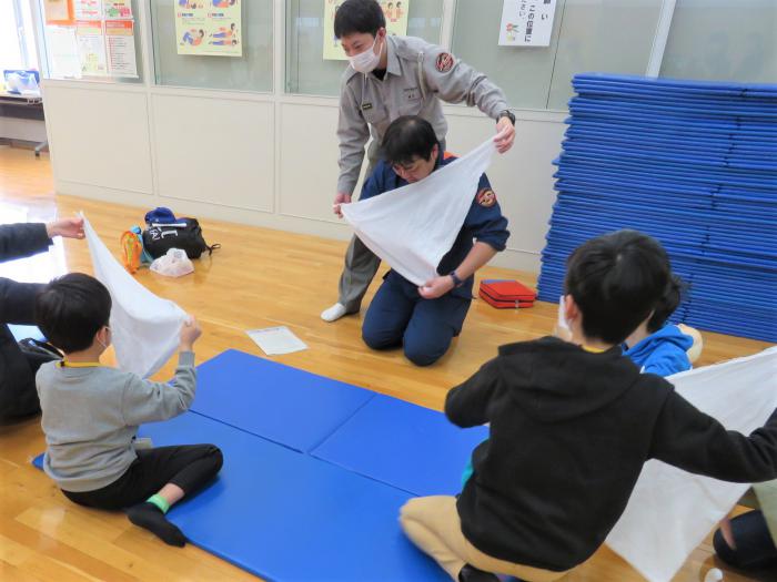 子どもが三角巾を使った応急手当の練習をしている様子