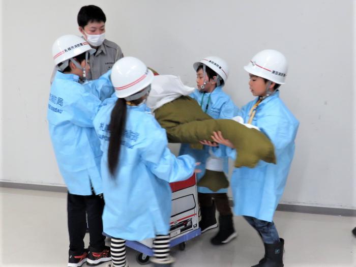 複数の子どもたちが傷病者に見立てたカエル人形を段ボールで作った救急車に乗せる様子