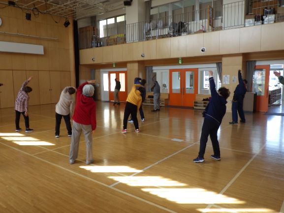 多目的室でラジオ体操をする地域の方と消防職員