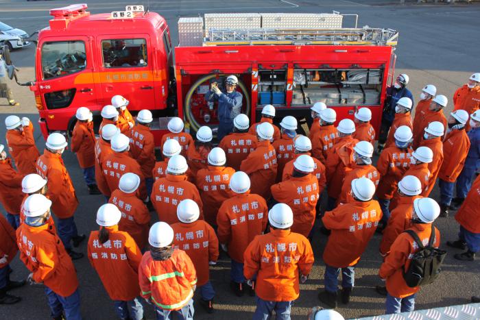 消防車両に積載されている機材の説明を受ける西消防団員