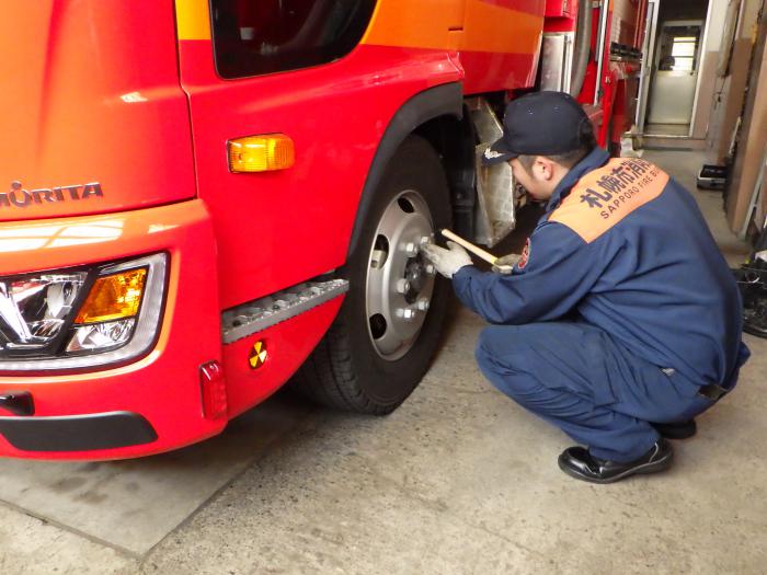 消防車のタイヤを点検する職員