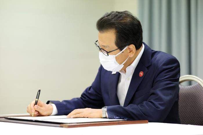 共同宣言文に署名する秋元克広札幌市長